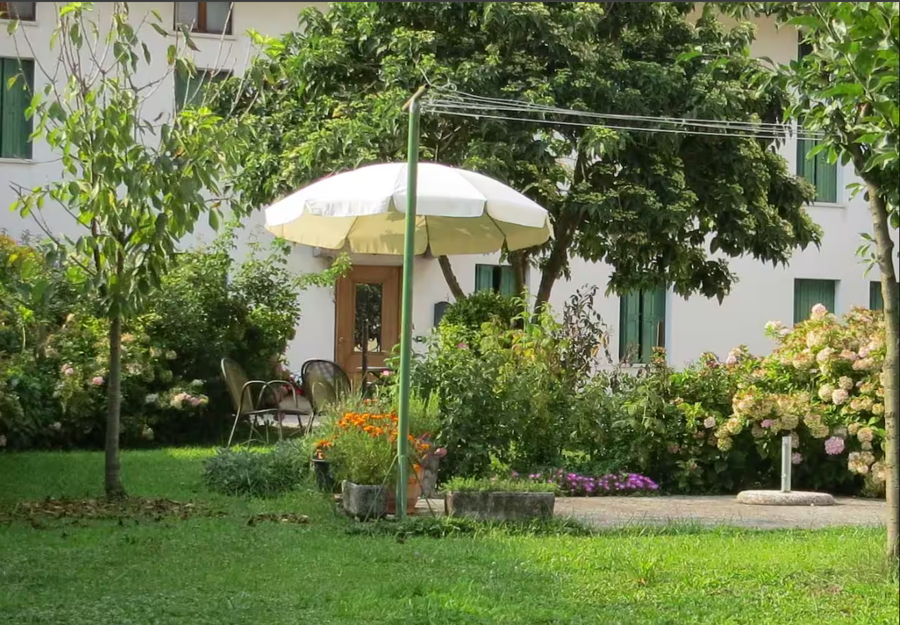 L'Antica Contea vista dal giardino: la casa intonacata con l'ombrellone e le ortensie