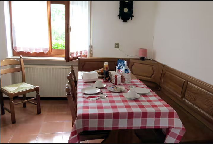 Sala da pranzo con tavolo, panca in legno e finestra sul giardino